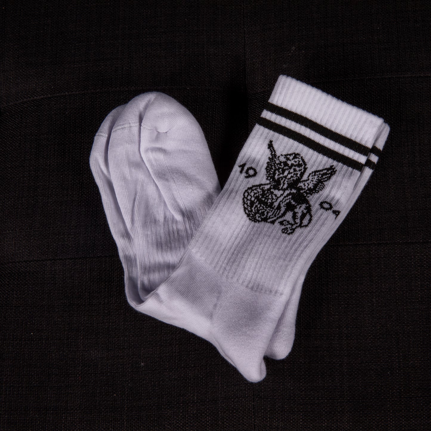 Weiße Socken mit schwarzen Streifen, teilweise ausgepackt – das geflügelte Löwenmotiv und die Zahl 1904 sind gut sichtbar.