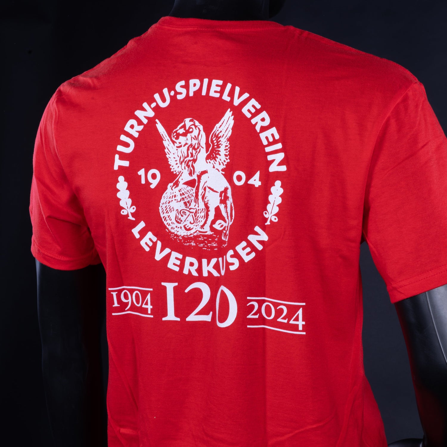Rückseite eines roten T-Shirts mit großem weißen Vereinslogo „Turn- und Spielverein Leverkusen 1904“ und darunter erneut „1904 120 2024“.