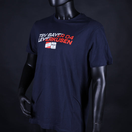 Dunkelblaues Kinder-T-Shirt mit dem Aufdruck „TSV Bayer 04 Leverkusen“ in Weiß und Rot sowie einem kleinen Vereinslogo darunter, präsentiert auf einer Schaufensterpuppe vor schwarzem Hintergrund.