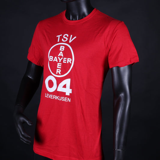 Rotes Kinder-T-Shirt mit großem weißen Vereinslogo „TSV Bayer 04 Leverkusen“ auf der Vorderseite, präsentiert an einer Schaufensterpuppe vor schwarzem Hintergrund.