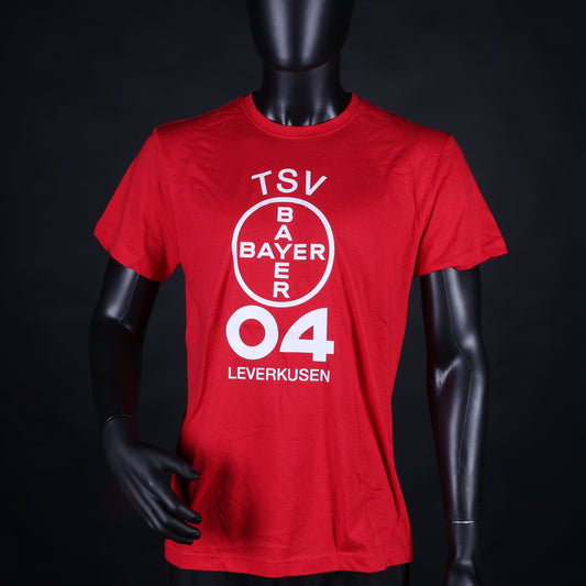 Rotes T-Shirt mit großem, vertikal ausgerichtetem TSV Bayer 04 Leverkusen Logo in Weiß auf der Vorderseite, präsentiert an einer Schaufensterpuppe vor schwarzem Hintergrund.