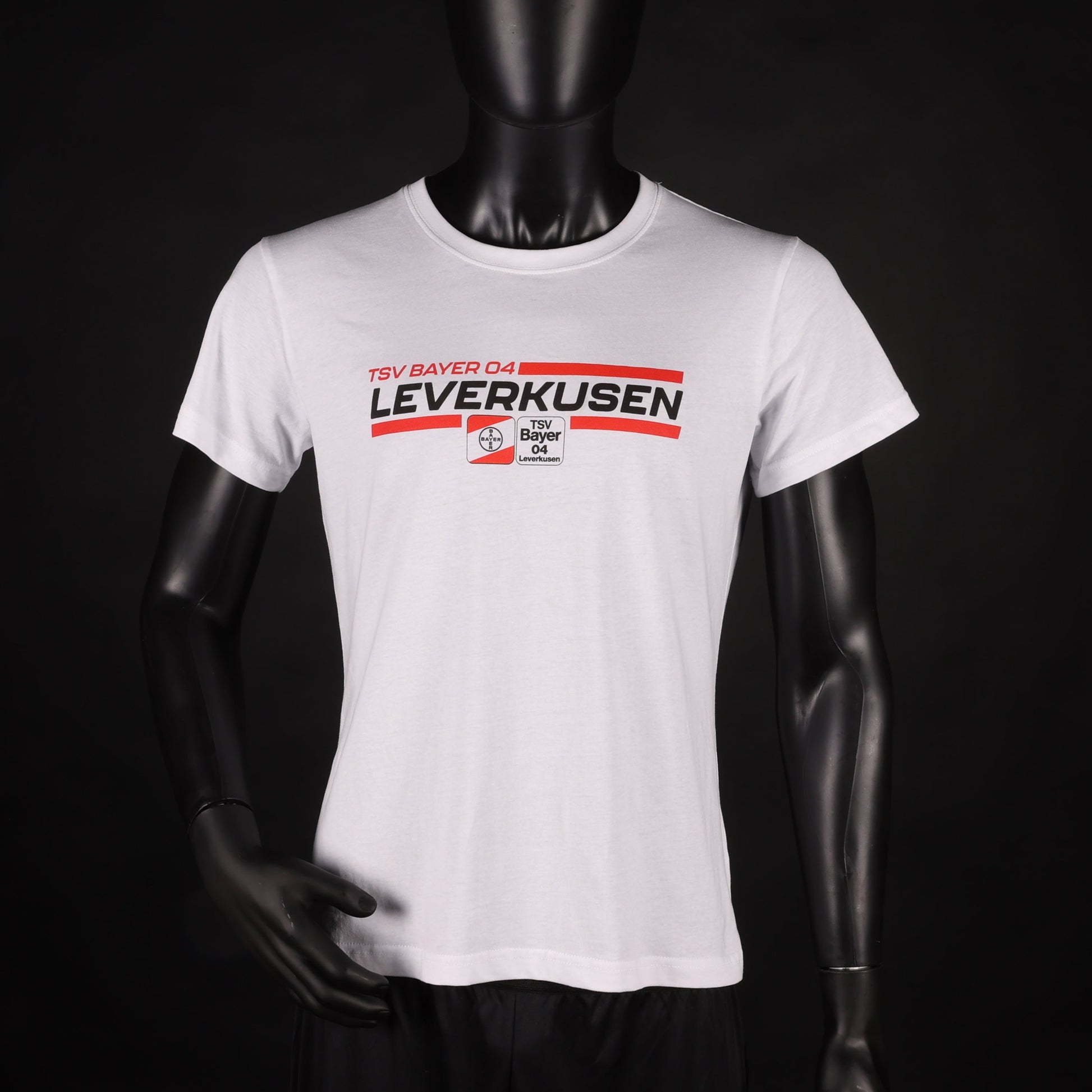 Weißes T-Shirt mit rotem und schwarzem „TSV Bayer 04 Leverkusen“-Schriftzug und Vereinslogo in der Mitte, präsentiert an einer Schaufensterpuppe vor schwarzem Hintergrund.
