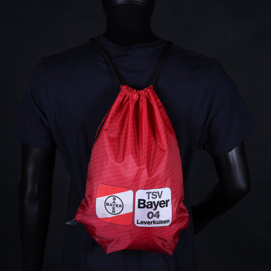 Roter Turnbeutel mit schwarzem Kordelzug, getragen auf dem Rücken einer Schaufensterpuppe; aufgedrucktes TSV Bayer 04 Leverkusen Logo in Weiß und Schwarz.