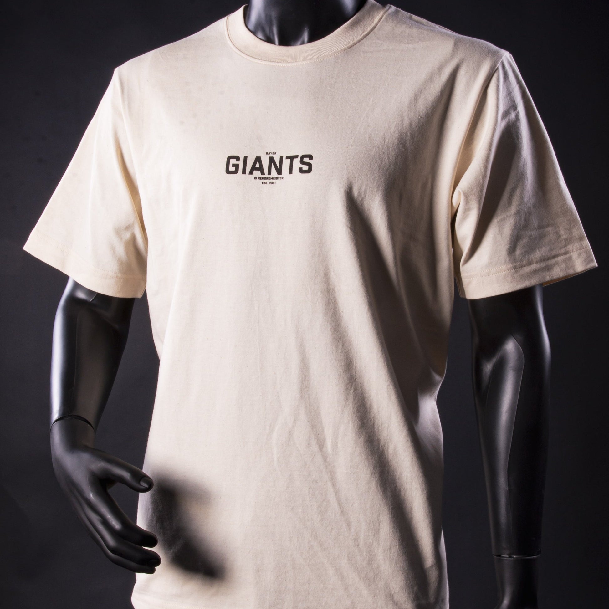 Beigefarbenes T-Shirt der Bayer Giants Leverkusen mit kleinem schwarzem Brustaufdruck ‚Bayer Giants – Basketball EST. 1961‘, getragen von einer Schaufensterpuppe.