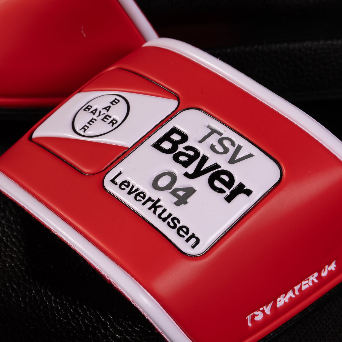 Detailaufnahme des Logos auf der TSV Bayer 04 Leverkusen Badelatsche mit deutlich sichtbarer Vereinsaufschrift und roten Designelementen.