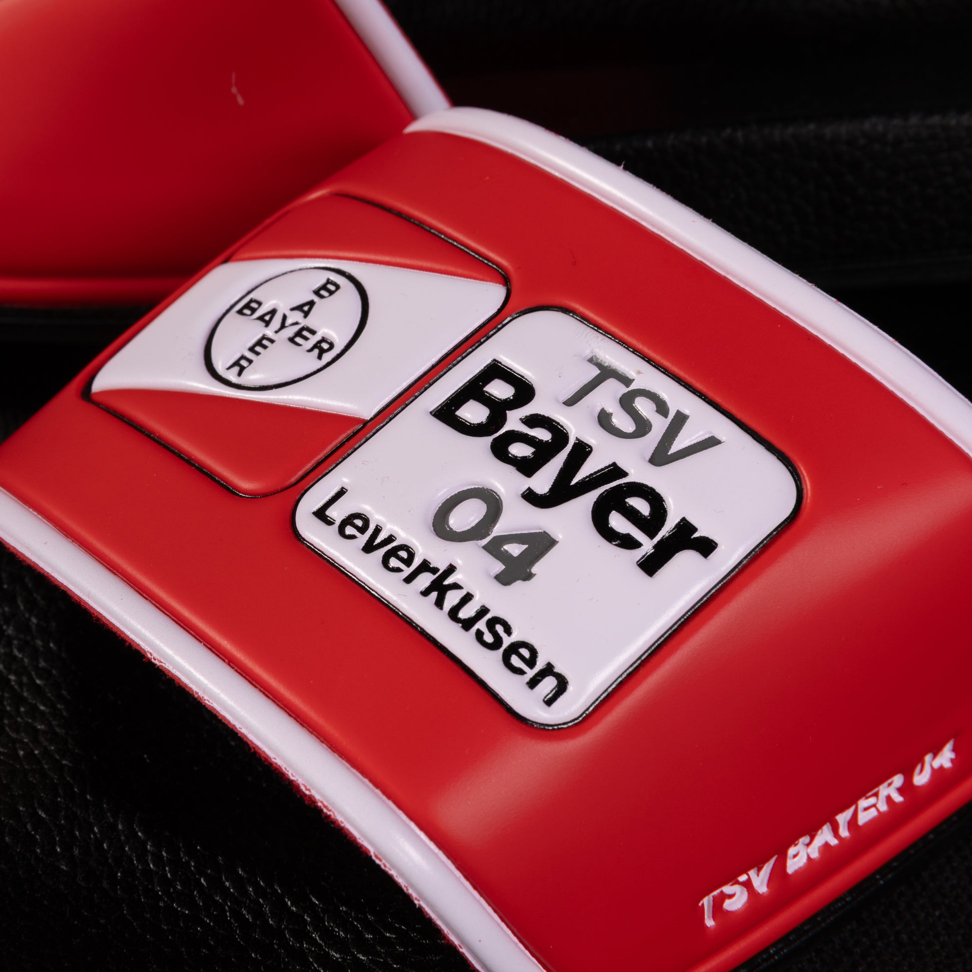 Detailaufnahme des Logos auf der TSV Bayer 04 Leverkusen Badelatsche mit deutlich sichtbarer Vereinsaufschrift und roten Designelementen.