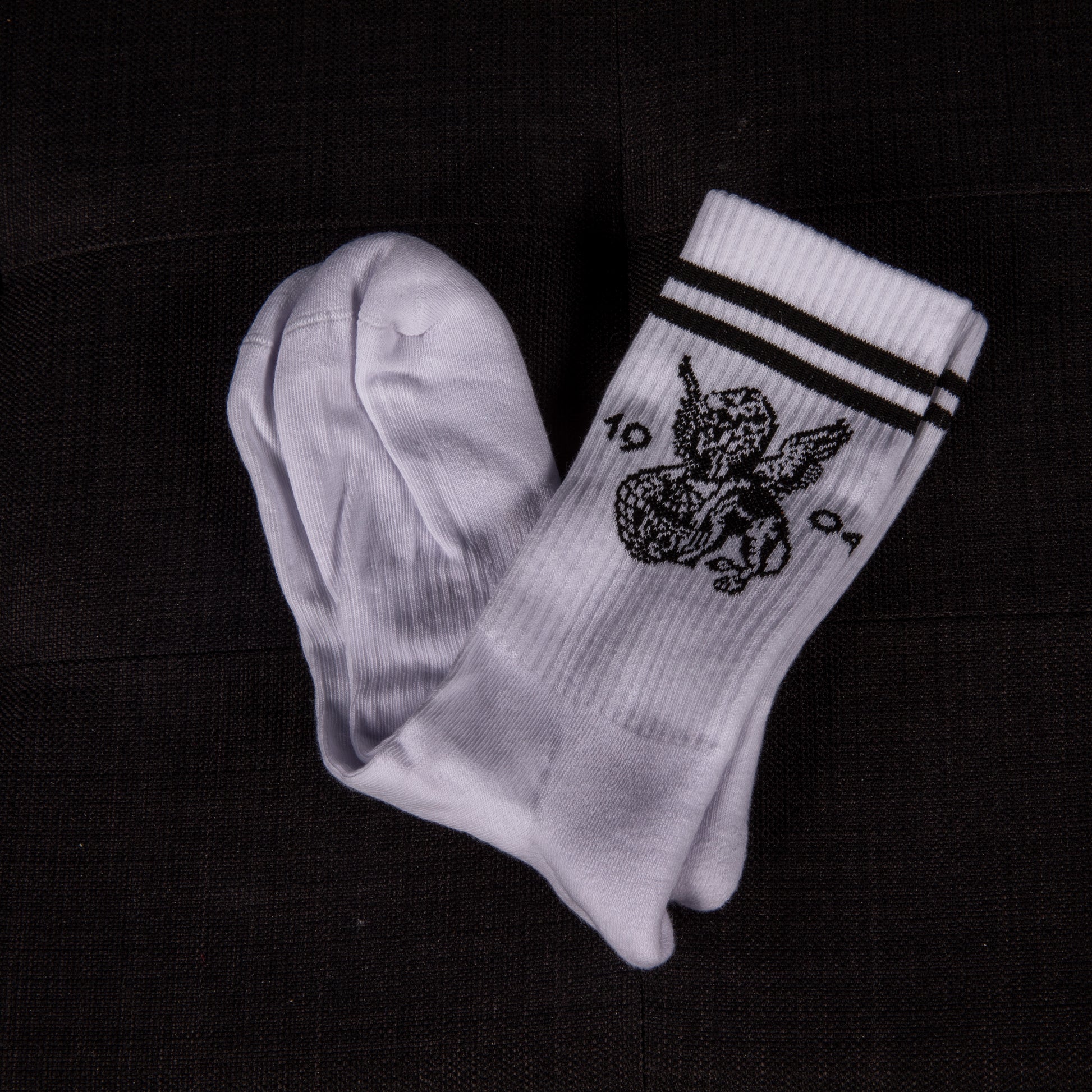 Weiße Socken mit schwarzen Streifen, teilweise ausgepackt – das geflügelte Löwenmotiv und die Zahl 1904 sind gut sichtbar.